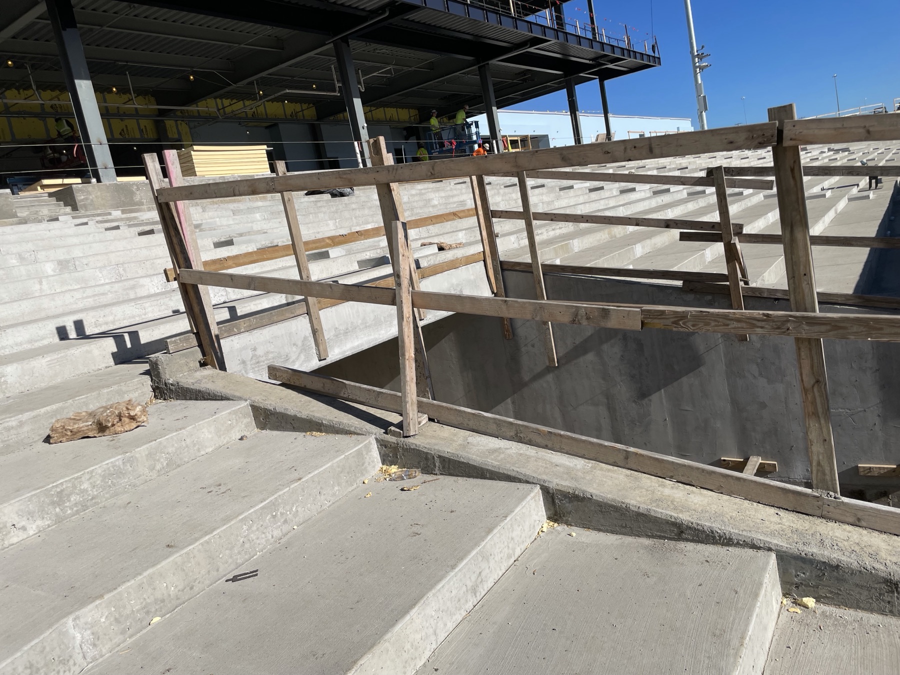 An arena construction area with stepped concrete and temporary rails.